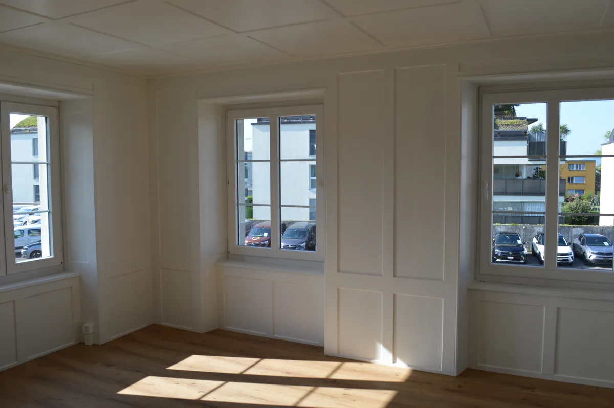 Ein helles Zimmer mit Strukturen an den Wänden und Parkettboden.